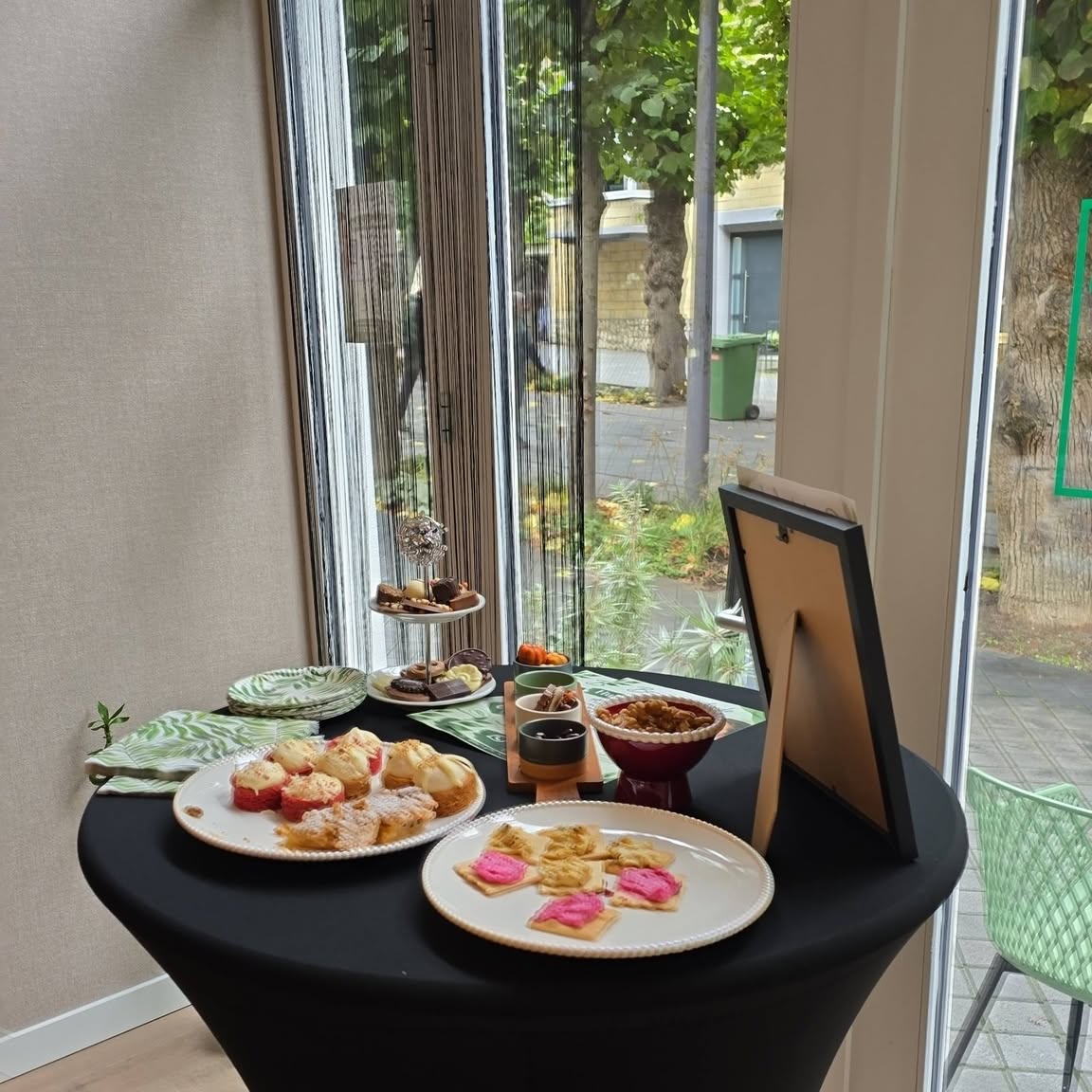 Een tafel met hapjes bij het raam, met de bomen van de Lindenlaan buiten